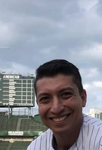 a man in a baseball uniform smiling in front of a stadium